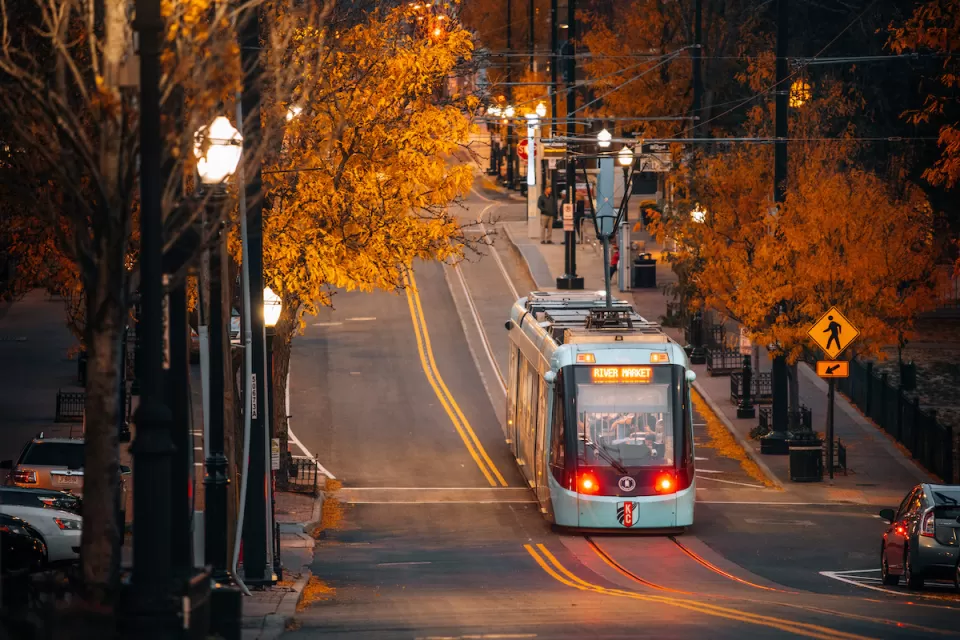 Kansas City streetcar running down street lined with trees in fall colors.